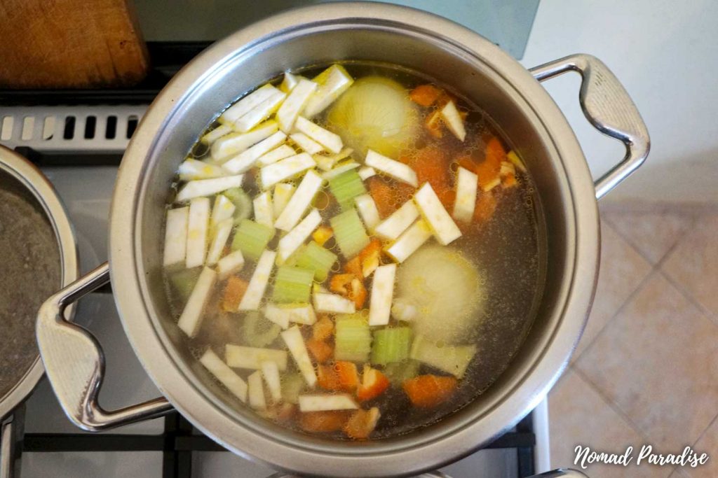 Making chicken noodle soup (adding celery, bell pepper, and black pepper to the pot).