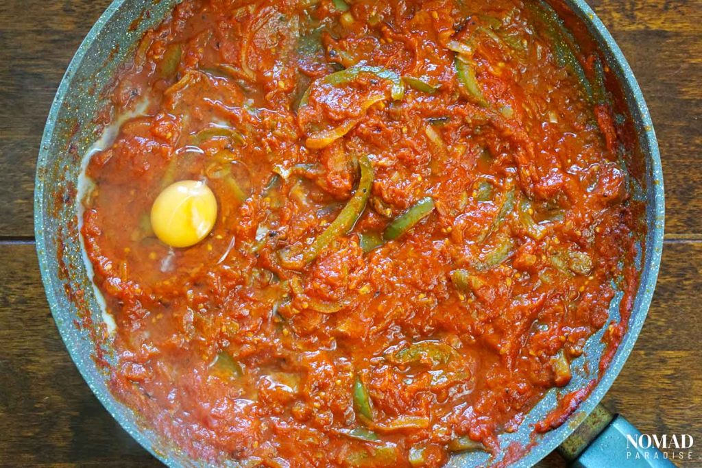 Shakshuka recipe step-by-step (cracking one egg in the pan).