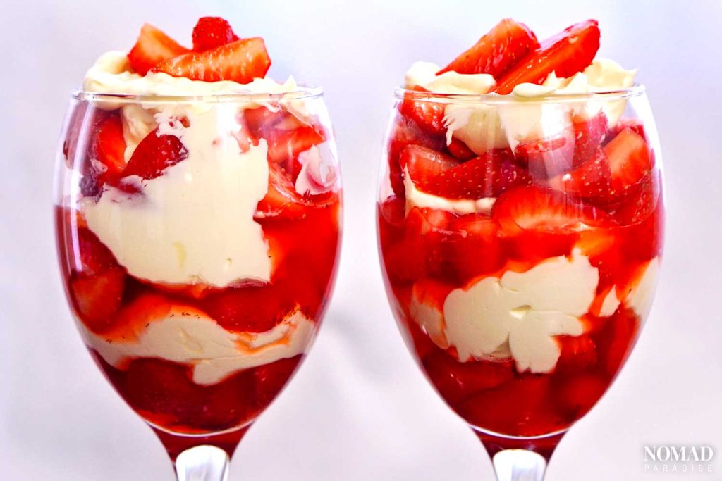 Strawberries and cream in two glasses side by side.