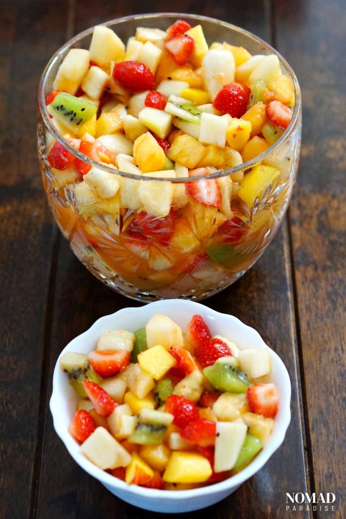 Fruit salad served in a large crystal bowl and an individual portion in a small white bowl.
