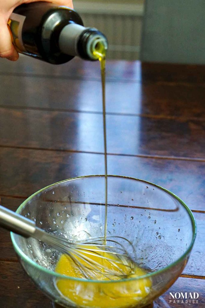 Making the vinaigrette (drizzling olive oil while whisking the vinegar in the bowl).