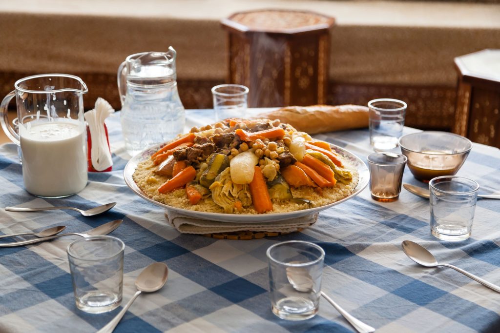 Couscous on a plate in the middle of a table with place settings around it