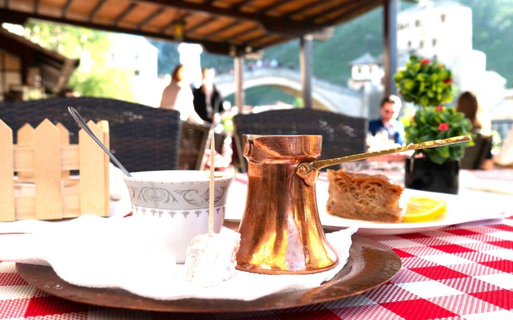Traditional Bosnian coffee on the table with the view of Mostar Old bridge in the background 