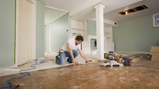 A man works on replacing the floor in the basement of a house.