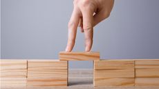 One wooden block spans two stacks of wooden blocks.