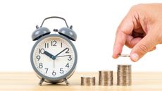 photo of a clock next to stacks of coins with a hand adding a coin