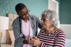 A caretaker looks after an older woman.