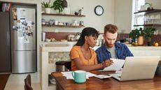 A couple look over their bills at the kitchen table.