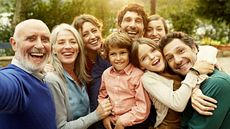 A multigenerational family takes a picture outdoors.