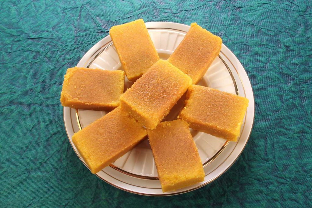 Indian dessert sweet, Mysore Pak, in the shape of bars, served on a plate.