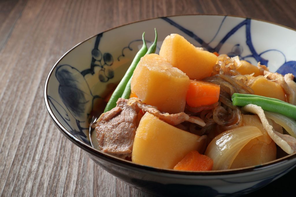 Nikujaga (a Japanese stew made with sliced beef, potatoes, onion, and carrots in dashi broth) served in a bowl.