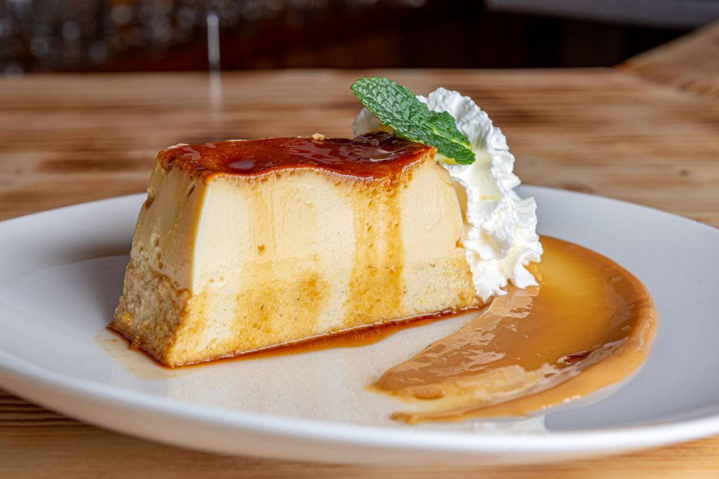 A slice of flan with dulce de leche on the side.