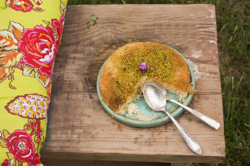 Knafeh on a serving plate with two spoons.