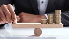 businessperson balancing coins on seesaw