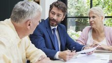 A couple sit with a financial adviser at a table.