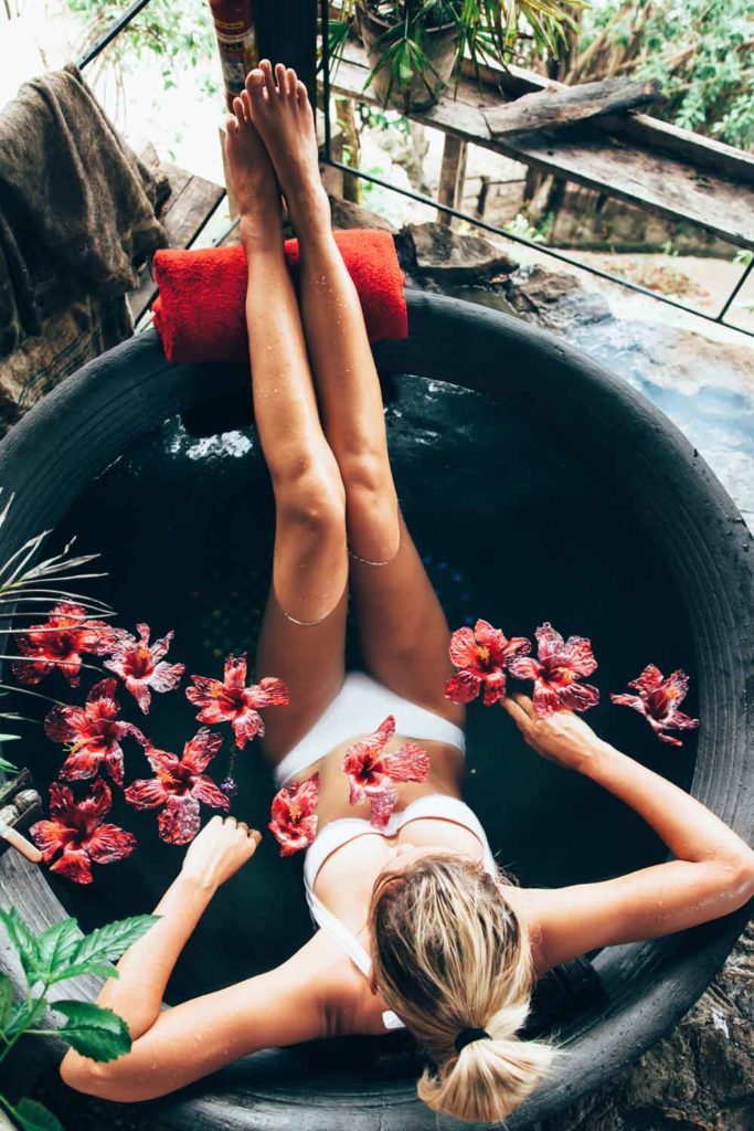 Staycation idea: taking a bath in a beautiful tub with flowers/petals floating in the water.