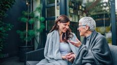 An older woman and a younger woman talk on the deck.